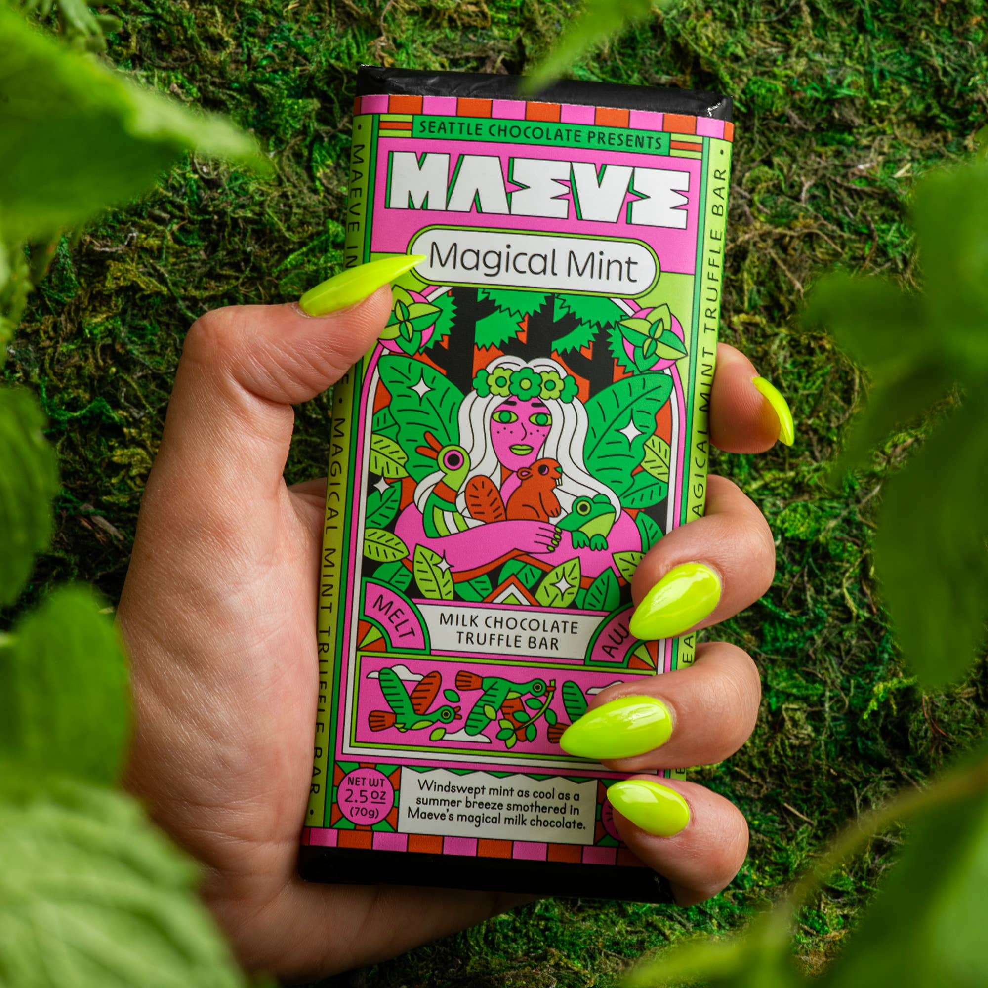 Hand holding a colorful chocolate bar packaging with 'Maeve' branding against a green leafy background