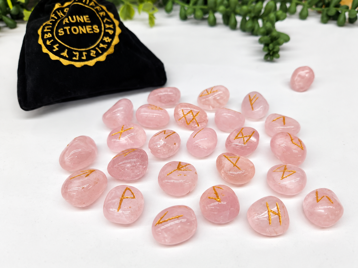 Rose Quartz Elder Futhark rune stone set with gold symbols and black storage pouch