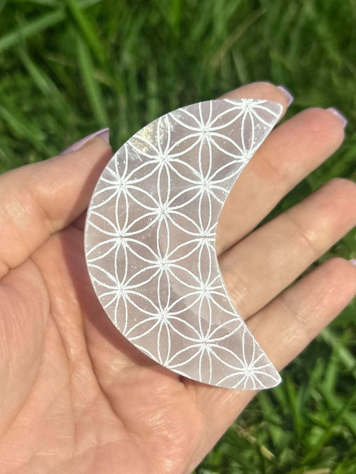 Carved selenite moon crystal featuring a Flower of Life pattern