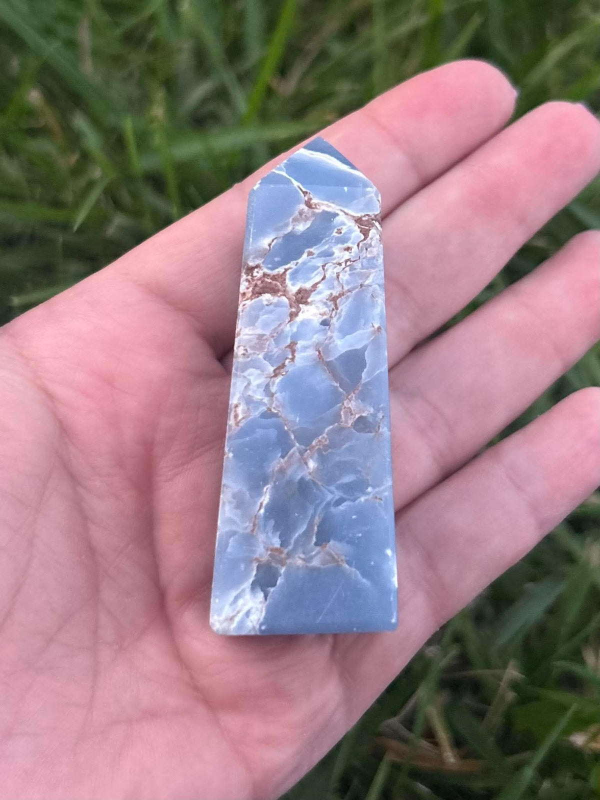 Blue Angelite crystal tower with natural white and brown matrix held outdoors in hand