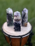 Three Rainbow Fluorite crystal towers with natural purple, green and clear banding displayed outdoors