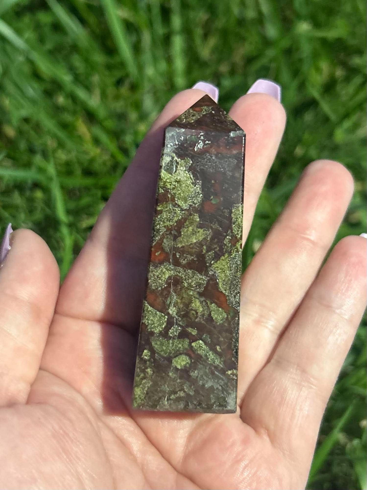 Dragon Blood Jasper crystal tower held in hand showing natural green and red patterning and approximate size