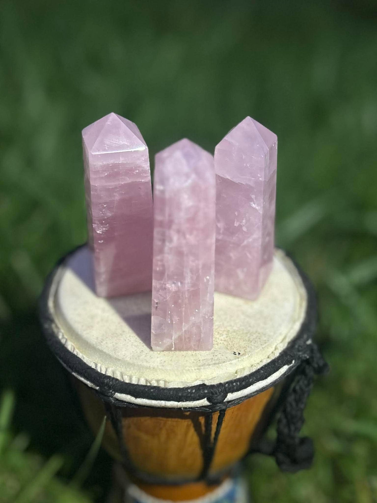 Natural Rose Quartz crystal towers with translucent pink coloring and polished points displayed outdoors
