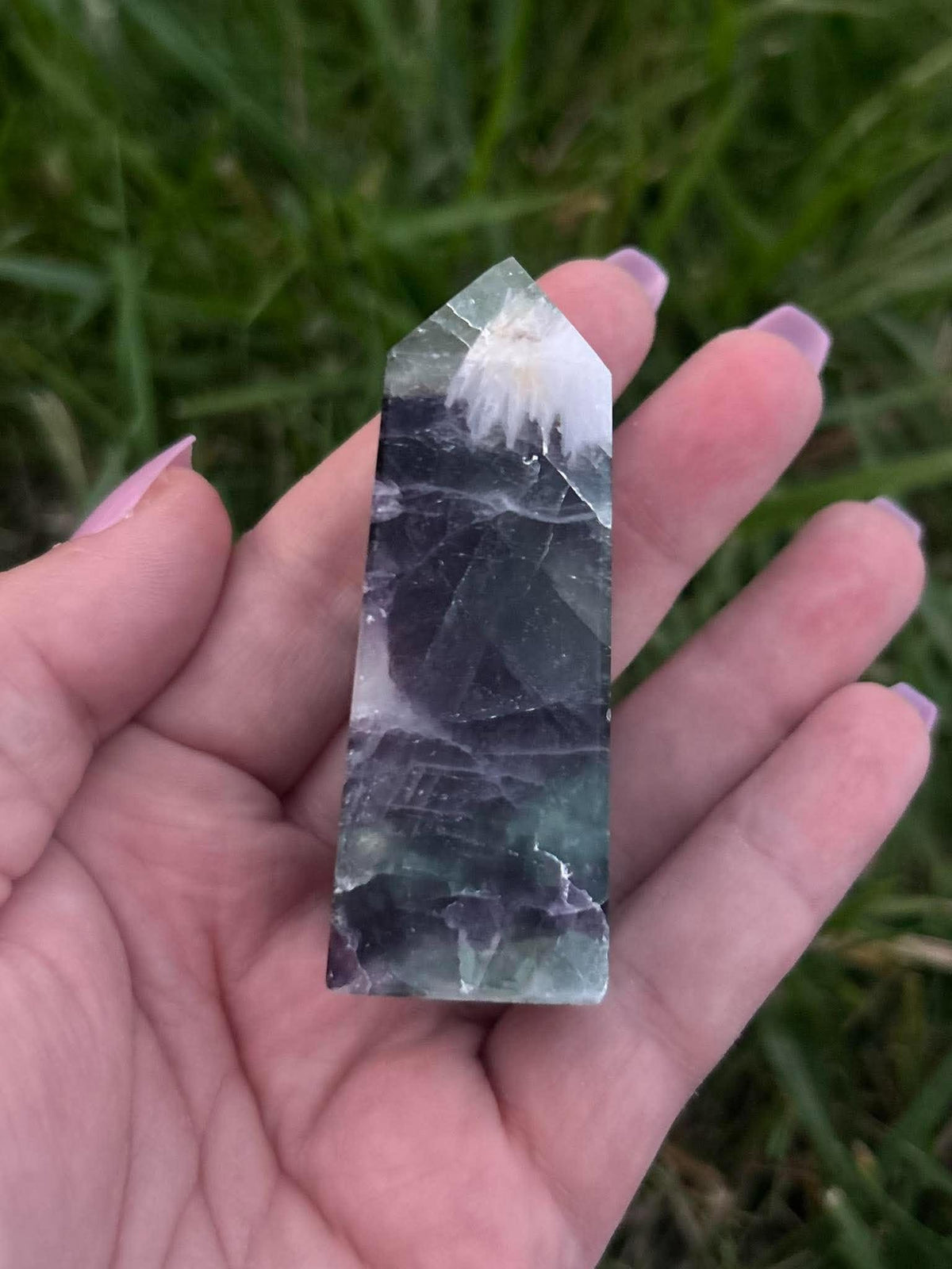 Rainbow Fluorite crystal tower held in hand showing approximately three-inch size and natural green, purple and clear bands