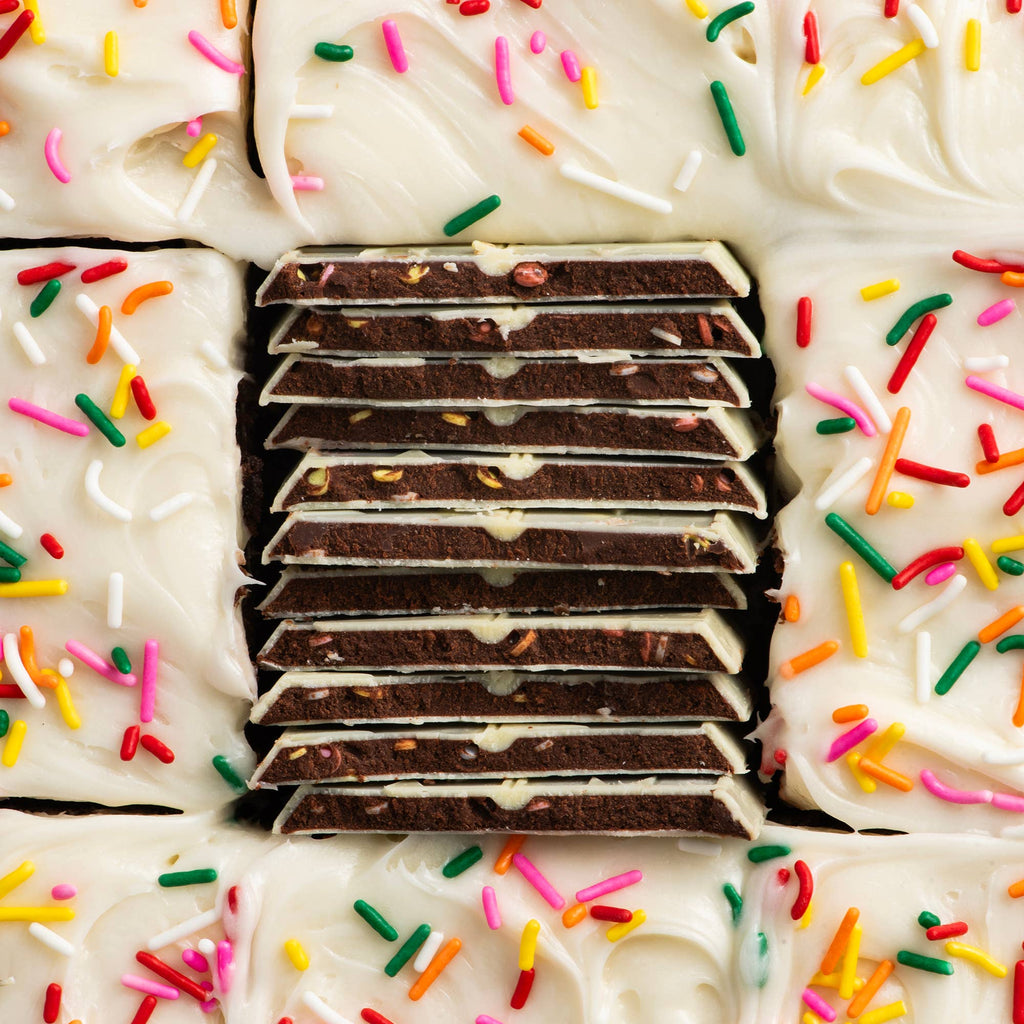Close-up of a layered dessert with white frosting and colorful sprinkles