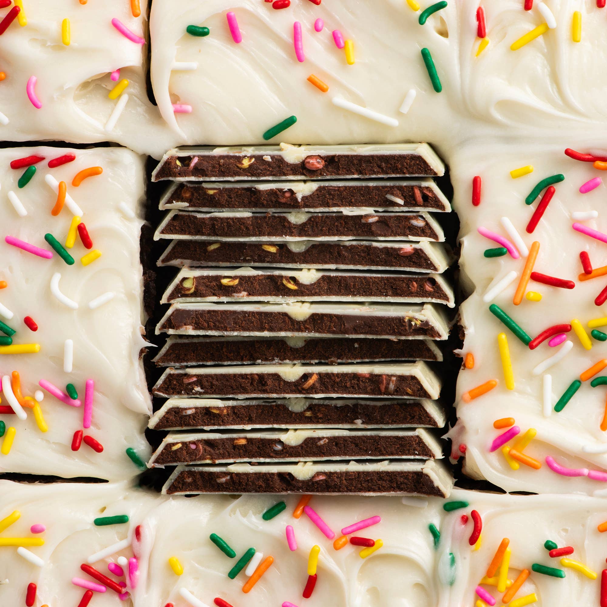 Close-up of a layered dessert with white frosting and colorful sprinkles